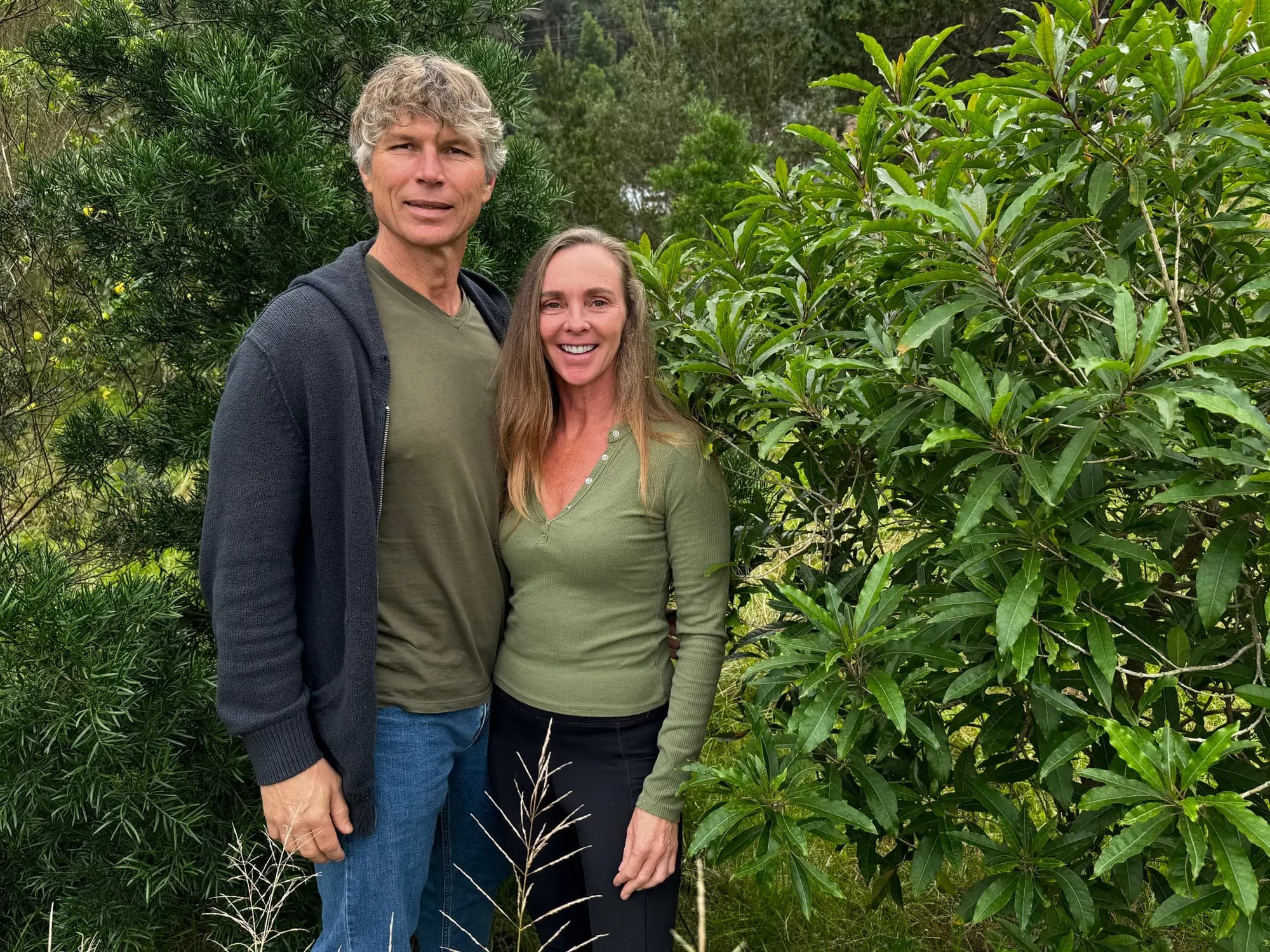 Vincent Cubitt and Mariette Carstens standing together among indigenous bush at Well-Being Sanctuary