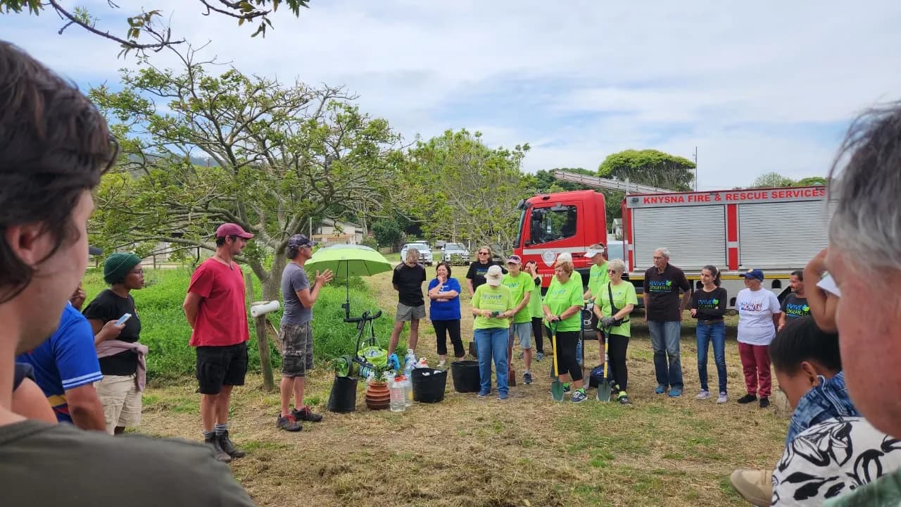 Volunteers gathered in a circle for the planting briefing, a Knysna Fire & Rescue truck parked behind them
