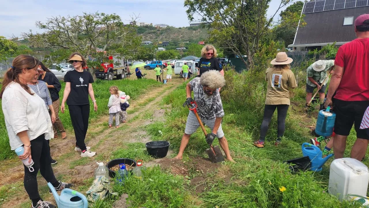Watering cans and water containers lined up as volunteers work along the planting rows